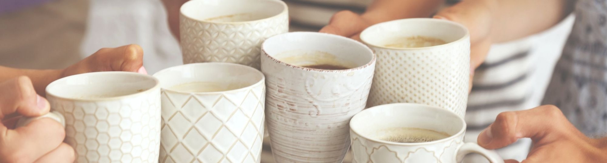 A group of people holding coffee mugs together