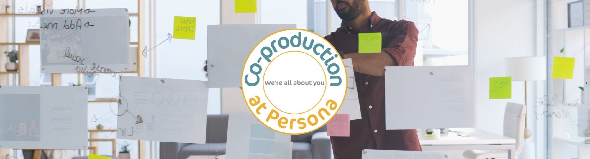 Image of a man sticking pieces of paper to a window with our co-production logo in the middle of the image