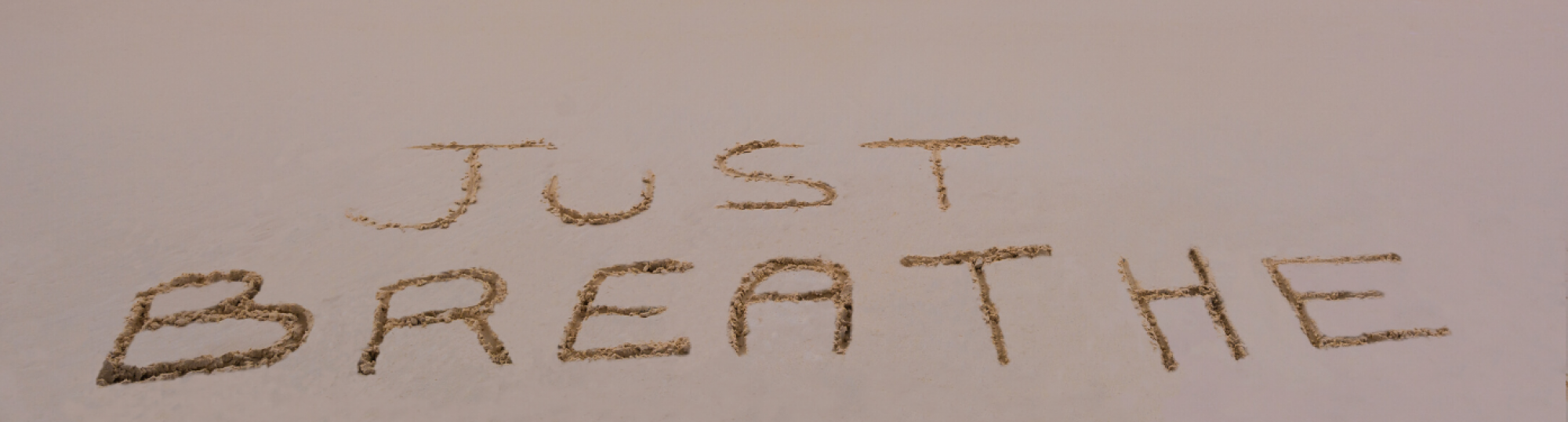 photo: 'just breathe' written in sand